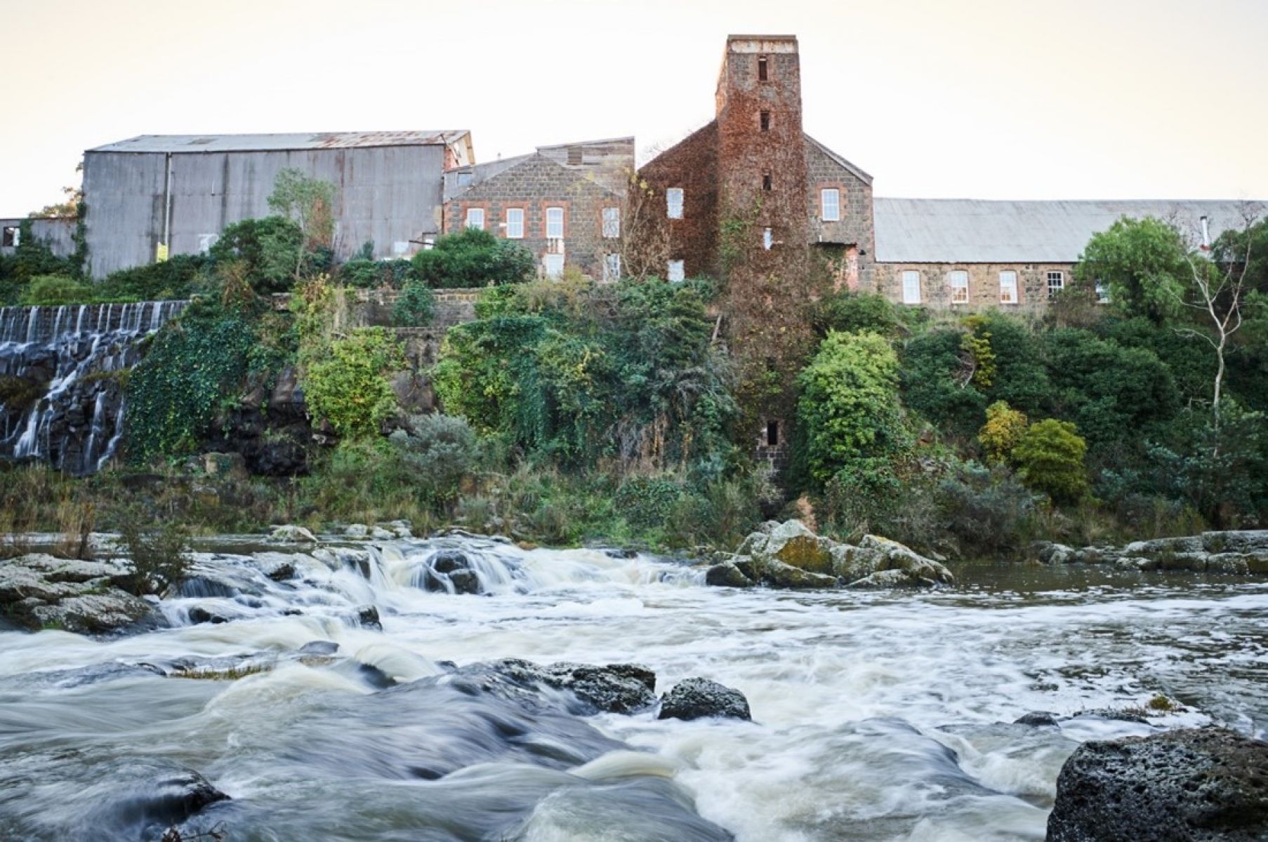The river flows past a disused industrial building