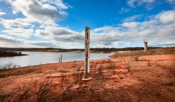 A river height gauge sits in red, dry earth.
