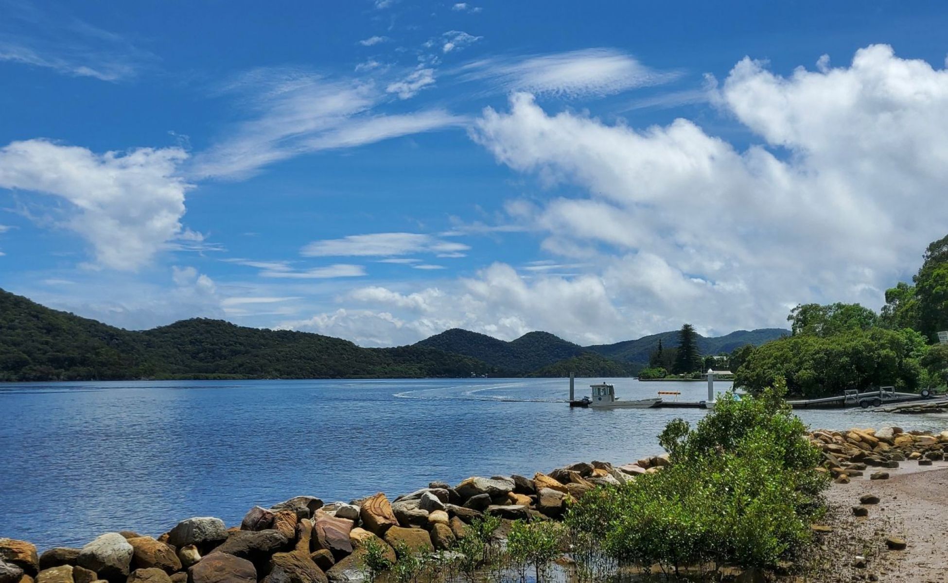 A boat along the shoreline of Lake Eildon with hills in the background and a shoreline in the foreground.