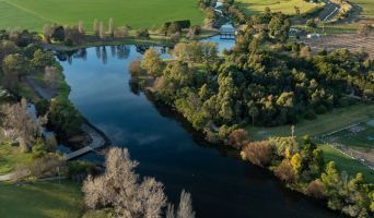 aerial photo of a river winds through a green landscape, trees and shrubs along its banks.