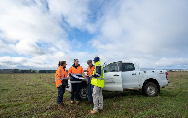 a group of people standing in a field standing next to a truck