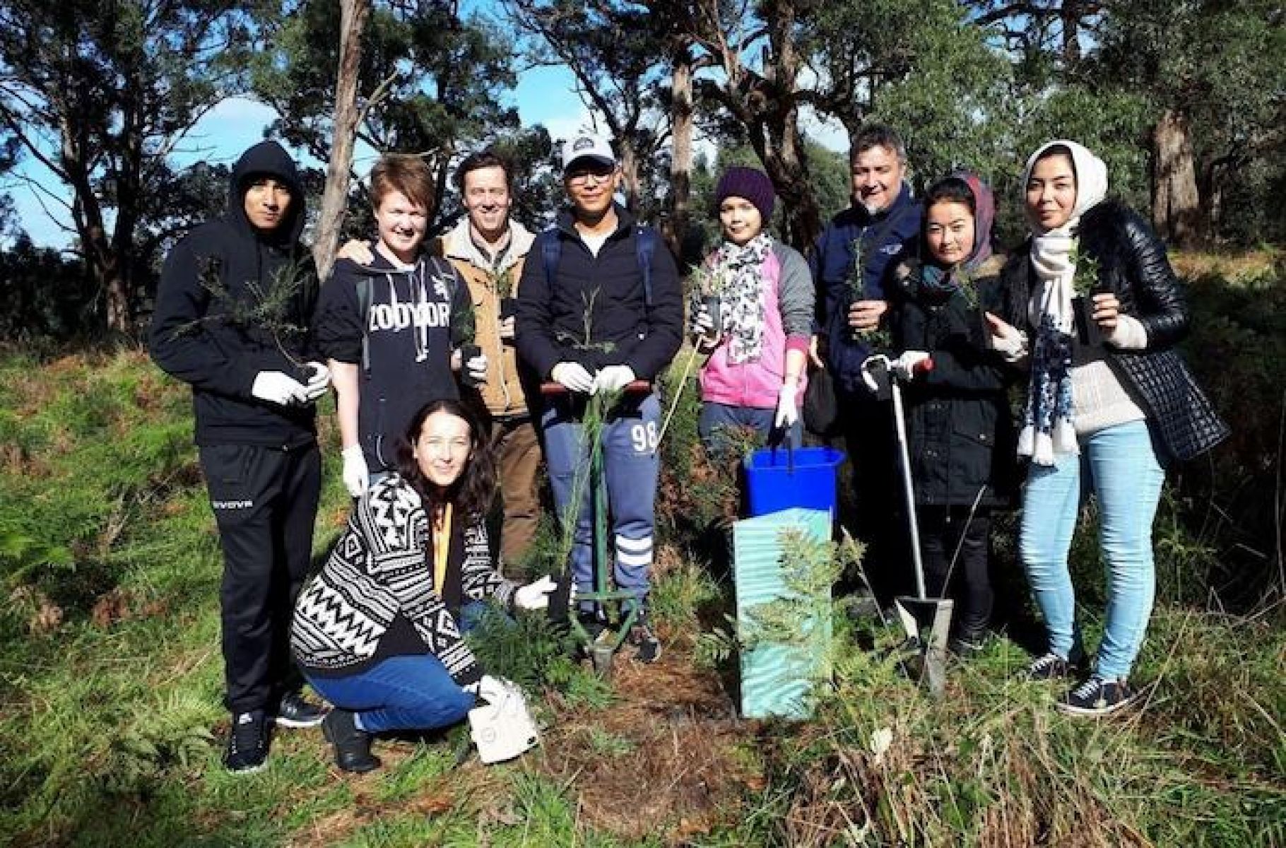 Group photo of adults and schoolchildren at a tree planting event.