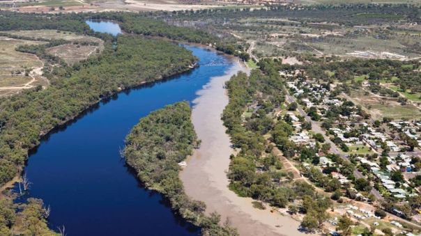 Two rivers, one which is muddy, converge with a town on one side.