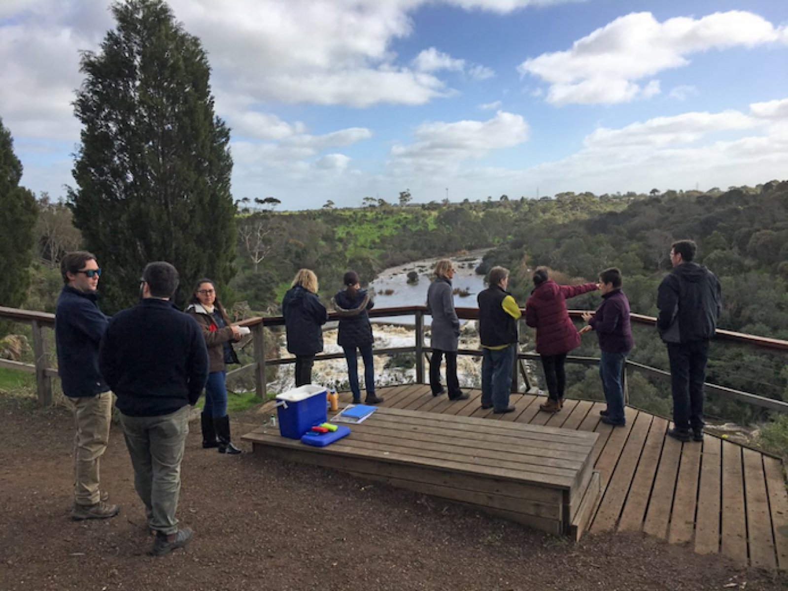 Photo of group of people standing on a ledge overlooking a river.