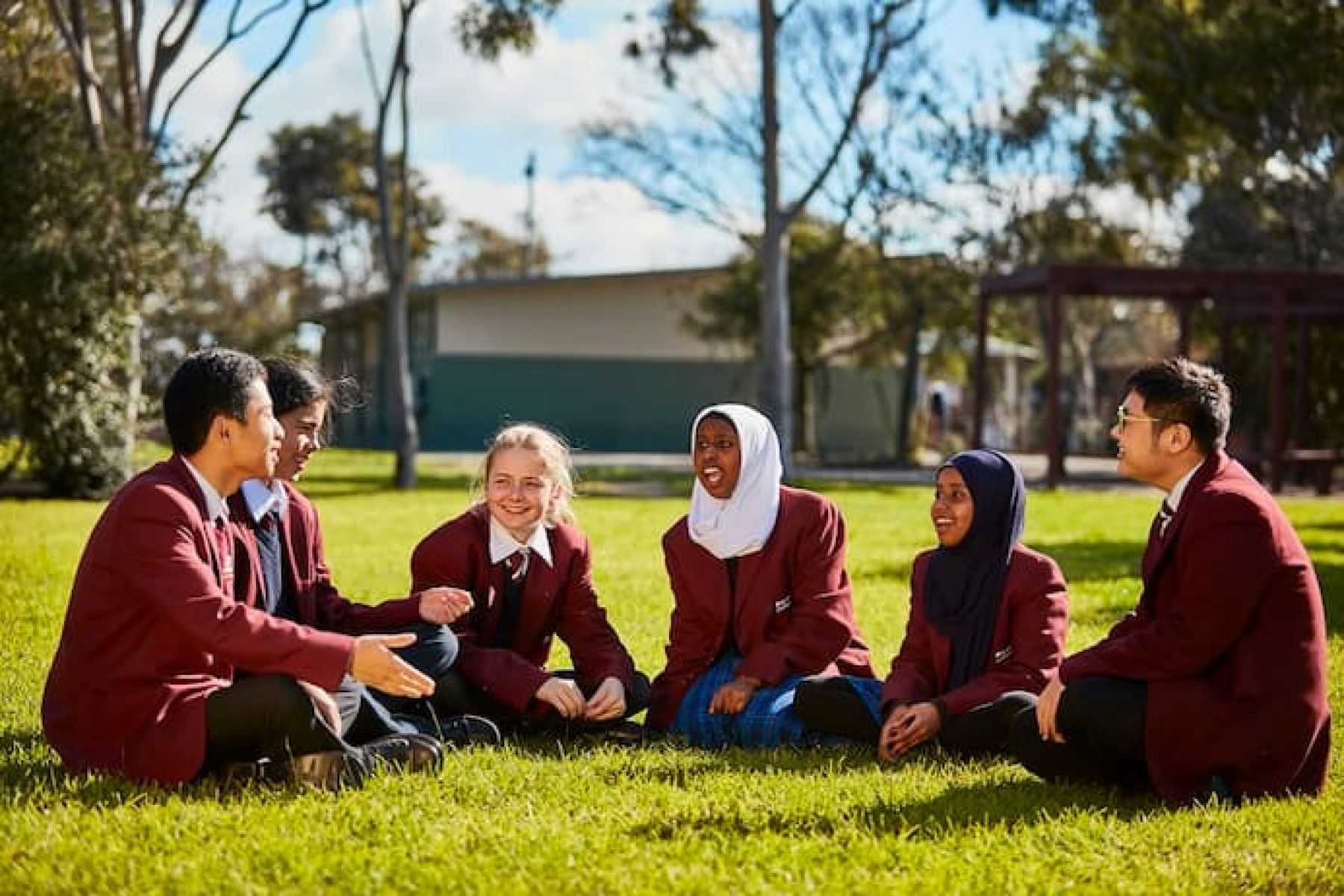 6 high school students sitting and having a conversation on a field