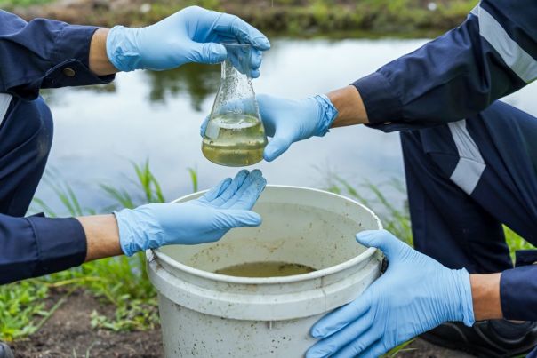 two people holding a beaker with water in it