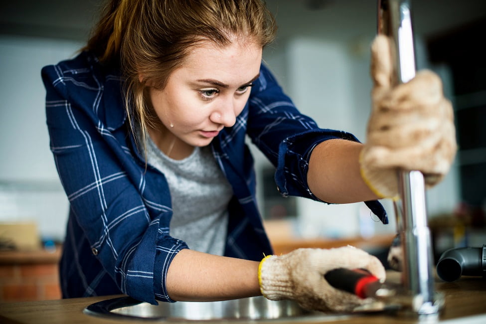 Female plumber using wrench on pipe