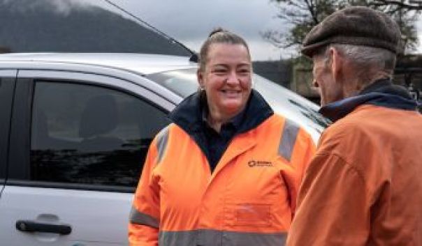 A water corporation officer wearing high-viz talks to a farmer.