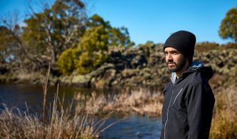 A Gunditj Mirring Traditional Owner stands looking outwards amid a wetland.