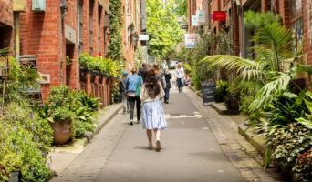 a woman walks down a Melbourne street that has been greenified with plants.