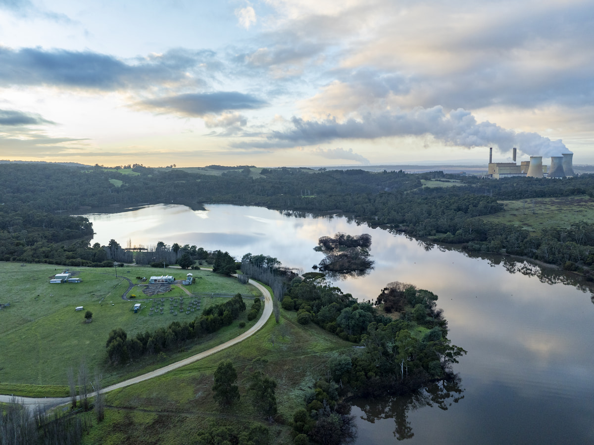 Aerial view of Lake Narracan with surrounding forest and farmland, and a power station with cooling towers in the distance.  