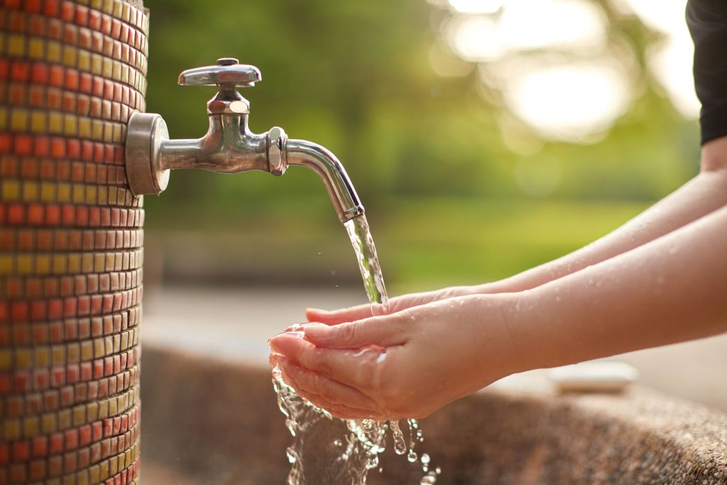 a person washing their hands outdoors at a park 