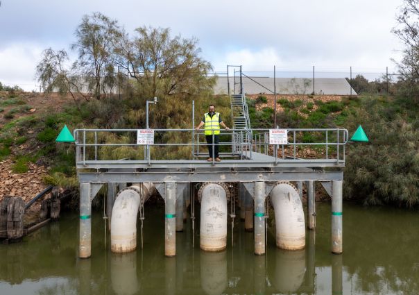 Pumping station with man standing over it on a riverbank